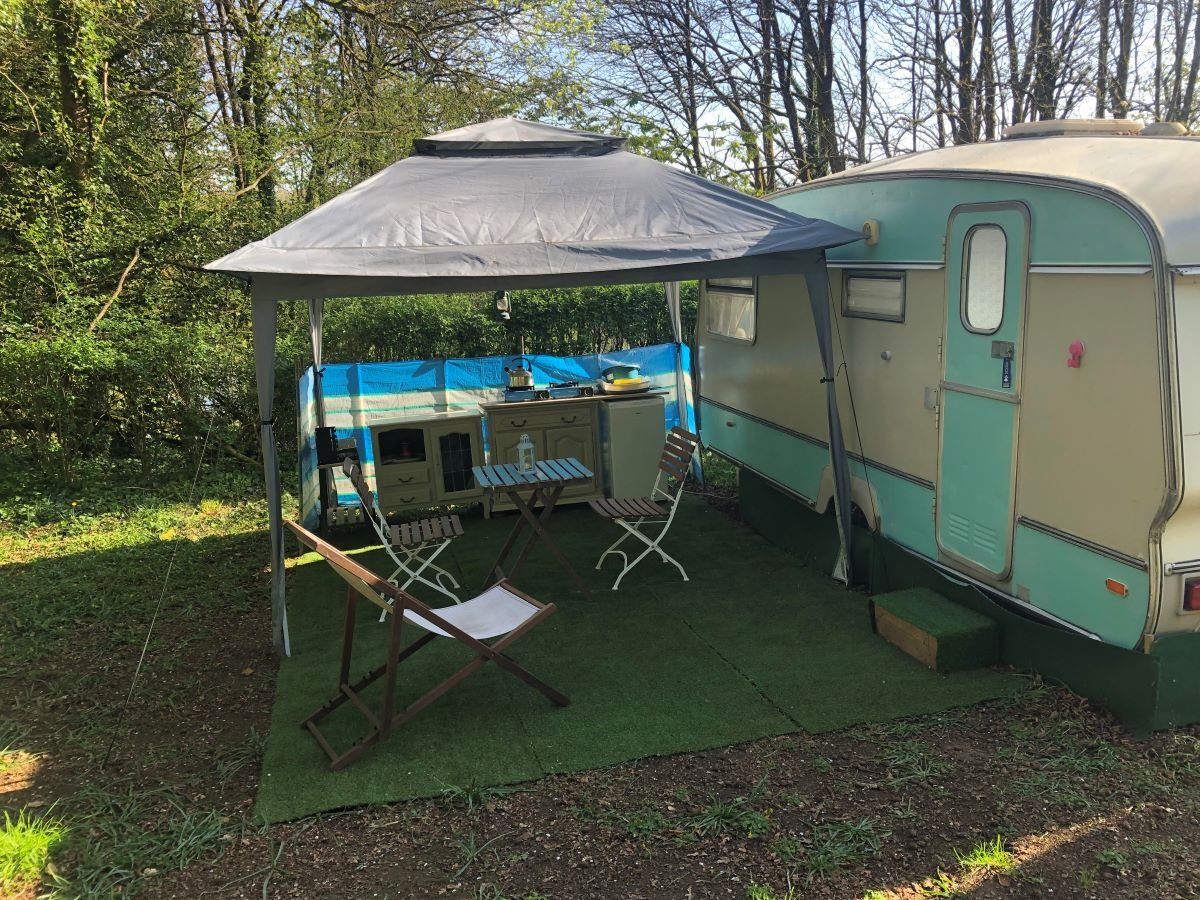 Caravan with awning, surrounded by trees
